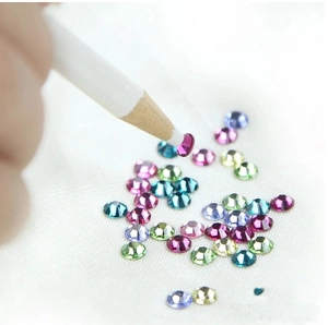 Macro shot of colorful nail art rhinestones and a white wax picker pencil tool