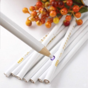 Close-up of a wax nail dotting pencil picking up a purple rhinestone for DIY nail art