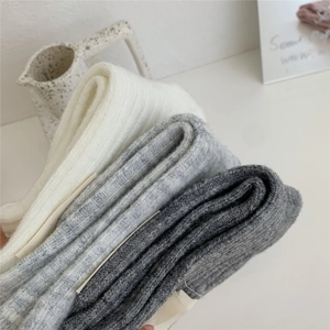Detail of soft ribbed wool blend socks in white and grey colors stacked neatly
