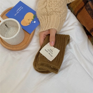 Close-up of thick brown knit wool socks featuring a minimalist white fabric brand label