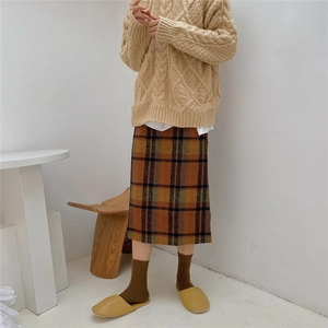 Close-up of thick brown wool socks styled with yellow flat slippers and a cozy sweater