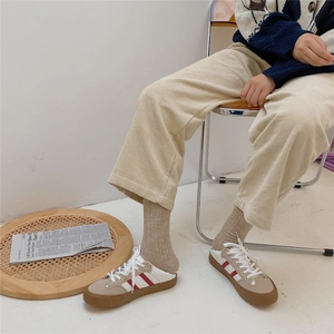 Detail shot of beige canvas sneakers styled with brown wool socks and corduroy pants