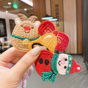 Detailed view of hand-made embroidered Christmas hair clips featuring reindeer and Santa
