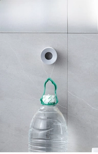 Adhesive wall hook on marble tile holding a heavy water bottle to show strong load capacity
