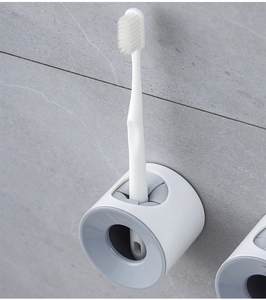 Wall-mounted electric toothbrush holder with adhesive backing on grey bathroom tile