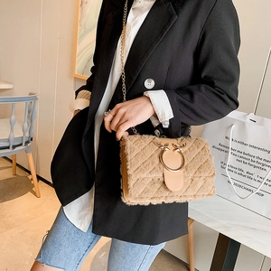 Detail of khaki plush crossbody bag featuring gold antler buckle and chain strap