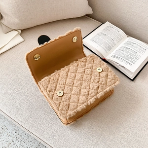 Khaki quilted plush flap crossbody bag with gold magnetic buckle on beige sofa decor