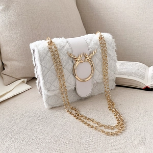 Detail of cream plush quilted crossbody bag featuring golden antler buckle and chain strap