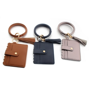 Detail of three leather wallet wristlet keychains with tassels and card slots in various colors