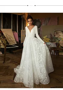 Détail de robe de mariée blanche avec col en V profond, manches longues et jupe dentelle
