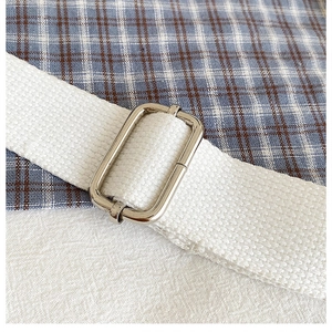 Detail of white canvas shoulder strap with silver metal adjustable buckle on bear bag