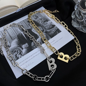 Detalle de collares con colgante de letra B en oro y plata sobre satén negro de lujo