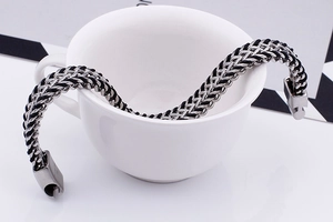 Detail of woven stainless steel chain bracelet with magnetic clasp on a white cup