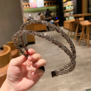 Detail of double-row black crystal headband with sparkling rhinestones held in hand