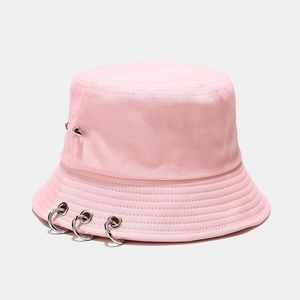 Détail d'un bob en toile rose avec des anneaux métalliques argentés et un rivet pointu