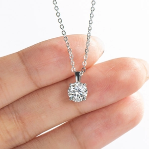 Close-up of 1 carat moissanite pendant held by hand showing silver 4-prong setting