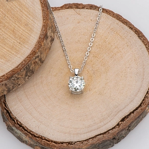 Macro shot of 1-carat moissanite necklace with four-prong silver setting on wood texture