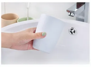Close-up of white matte toothbrush cup with anti-slip texture held by hand in a bathroom