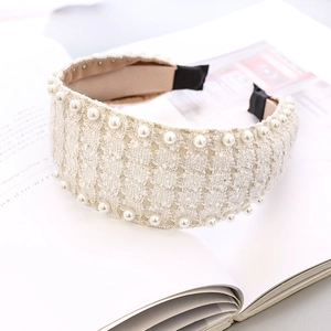 Detail of cream white tweed headband with elegant pearl trim on lifestyle magazine