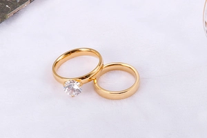 Detail von goldenen Pärchenringen mit rundem Zirkonia und poliertem, schlichtem Ringband