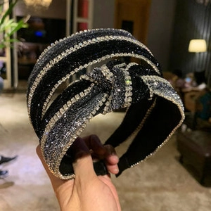 Detail of a wide twisted headband featuring sparkling silver rhinestones on navy fabric