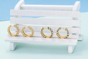 Macro shot of U-shaped gold punk earrings with colorful cubic zirconia and spike rivets