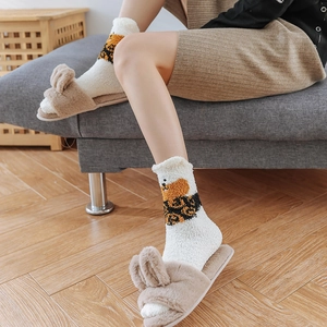 Close-up of cozy coral fleece socks with cute cartoon animal patterns and plush slippers