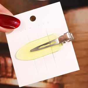 Detail einer lichtdurchlässigen gelben Haarspange mit Metallbasis auf weißer Karte
