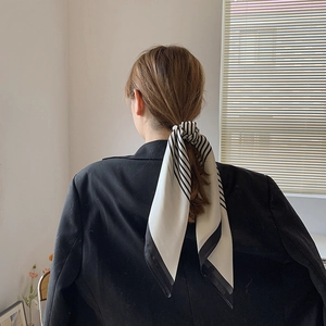Elegant black and white striped silk scarf tied as a hair accessory on a ponytail