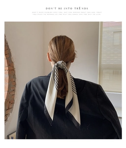 Close-up of black and white striped silk scarf styled as an elegant ponytail hair tie