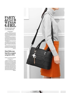 Detail of black woven leather tote bag with gold cat charm and tassel on a model
