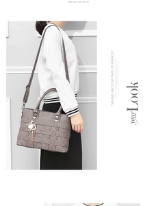 Detailed view of grey tote bag with woven texture, cat charm and adjustable strap