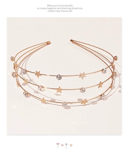 Close-up of triple-layered gold headband with star charms and sparkling rhinestones