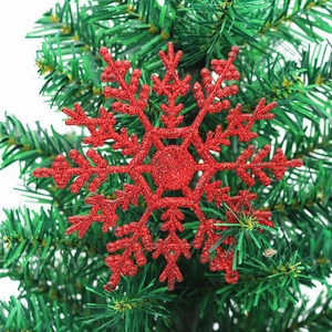 Sparkling red snowflake ornament with glitter finish hanging on a green Christmas tree