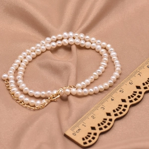 Detailed view of double-layer white freshwater pearl necklace with gold metal clasp