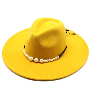 Detail of yellow wool fedora hat featuring black band with elegant white pearl accents