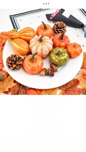 Close-up of decorative artificial pumpkins with pine cones and autumn maple leaves