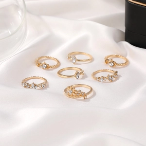 7-piece gold-toned celestial star and moon ring set with crystals on white silk fabric