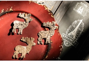 Macro detail of three reindeer ornaments crafted from natural tree bark on a red tray