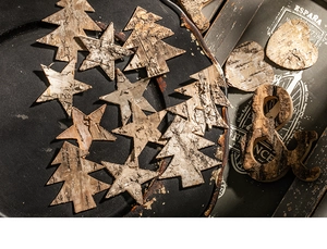 Detailed view of natural birch bark ornaments in tree, star, and heart shapes on metal tray