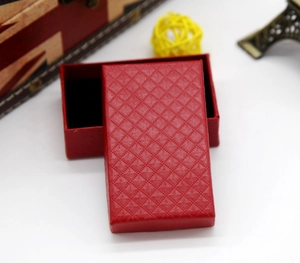 Detail shot of a red jewelry gift box featuring a textured diamond pattern on the lid surface