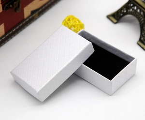 Close-up of a white rectangular jewelry box with diamond texture and black sponge lining