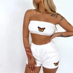 Détail de la texture en velours blanc avec broderie papillon orange sur le bas du short