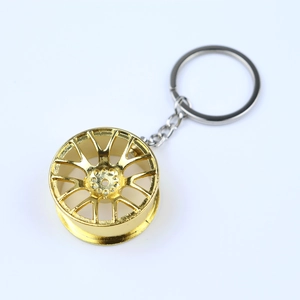 Detailed view of miniature gold metallic car wheel rim keychain with polished finish