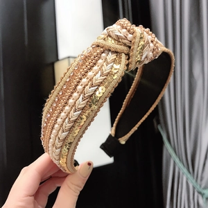 Close-up of knotted headband with woven fabric, embedded pearls, and sparkling rhinestones