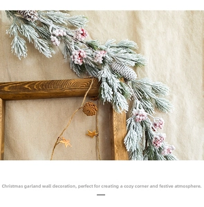 Detail of Christmas pine garland with artificial snow, red berries and natural pine cones