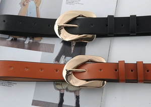 Detail view of black and brown leather belts with large golden irregular metal buckles