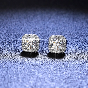 Macro shot of silver halo stud earrings with round moissanite center on textured blue background