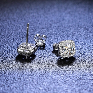 Macro shot of S925 sterling silver square halo moissanite stud earrings on blue leather