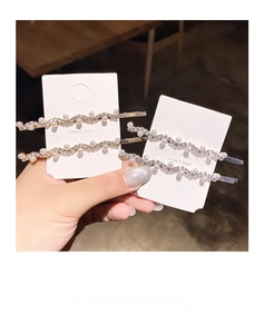 Close-up of pearl and rhinestone hair clips set on a display card in soft warm light